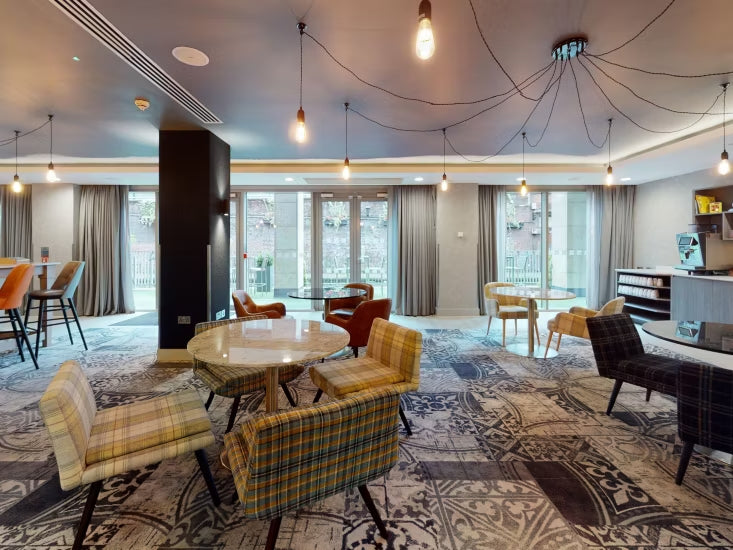 Modern living room with plaid chairs, round table, and large windows, manchester holiday inn central uk playing card convention cards in common