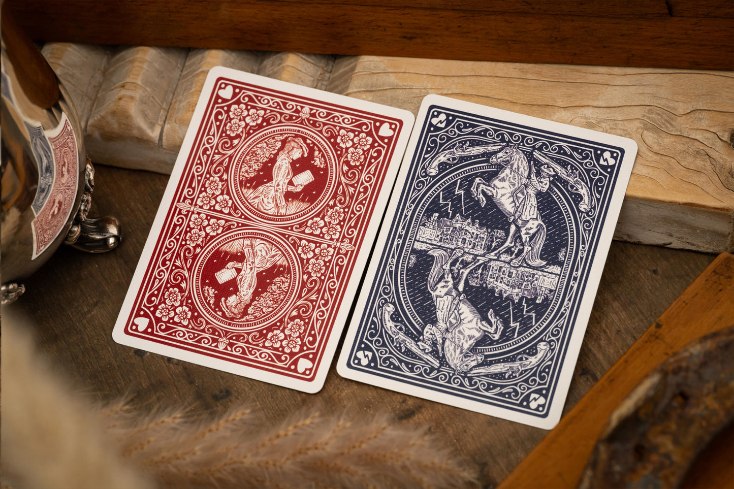 Two playing cards, one red and one blue, on a wooden surface.
