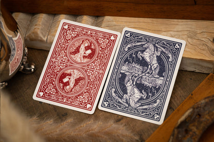 Two playing cards, one red and one blue, on a wooden surface.