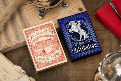 Two playing card decks, one red and one blue, on a wooden surface with vintage books and objects.