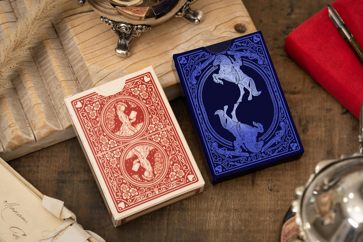 Two playing card decks, one red and one blue, on a wooden surface with vintage items.