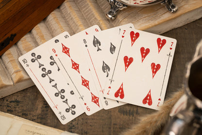 Playing cards on a wooden surface with a cup and saucer in the background