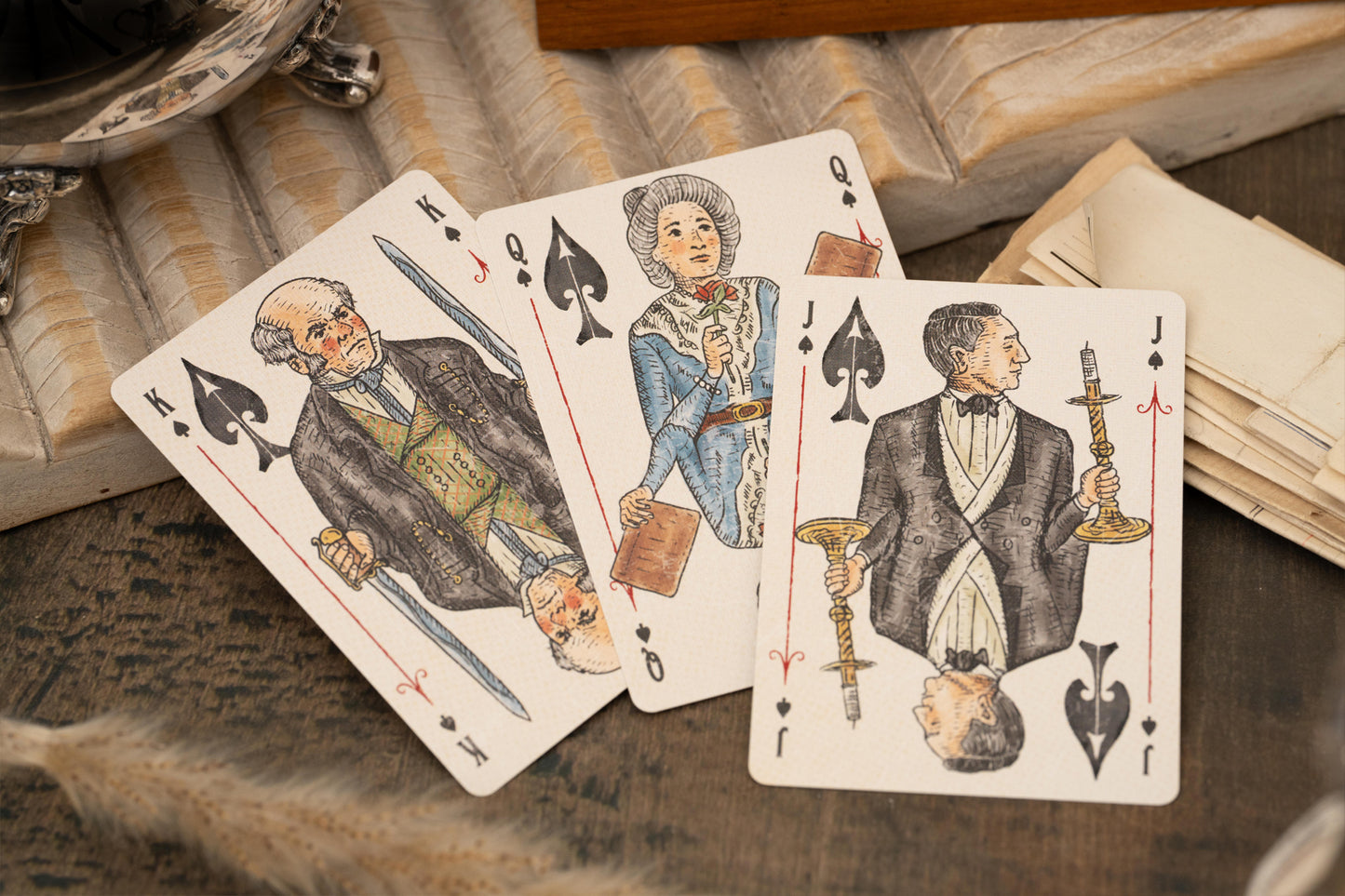 Vintage Love & Retribution illustrated character courts playing cards with intricate designs on a textured surface