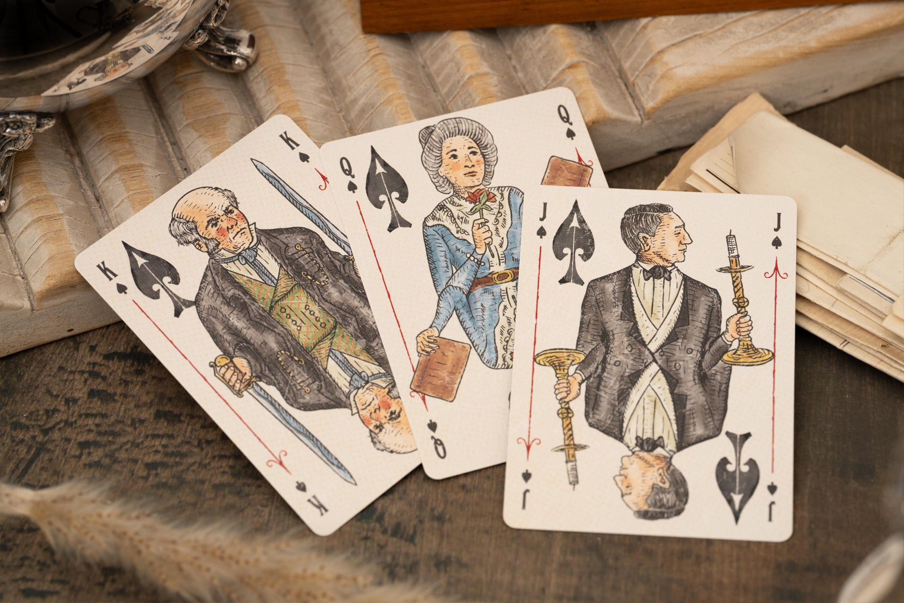 Vintage Love & Retribution illustrated character courts playing cards with intricate designs on a textured surface