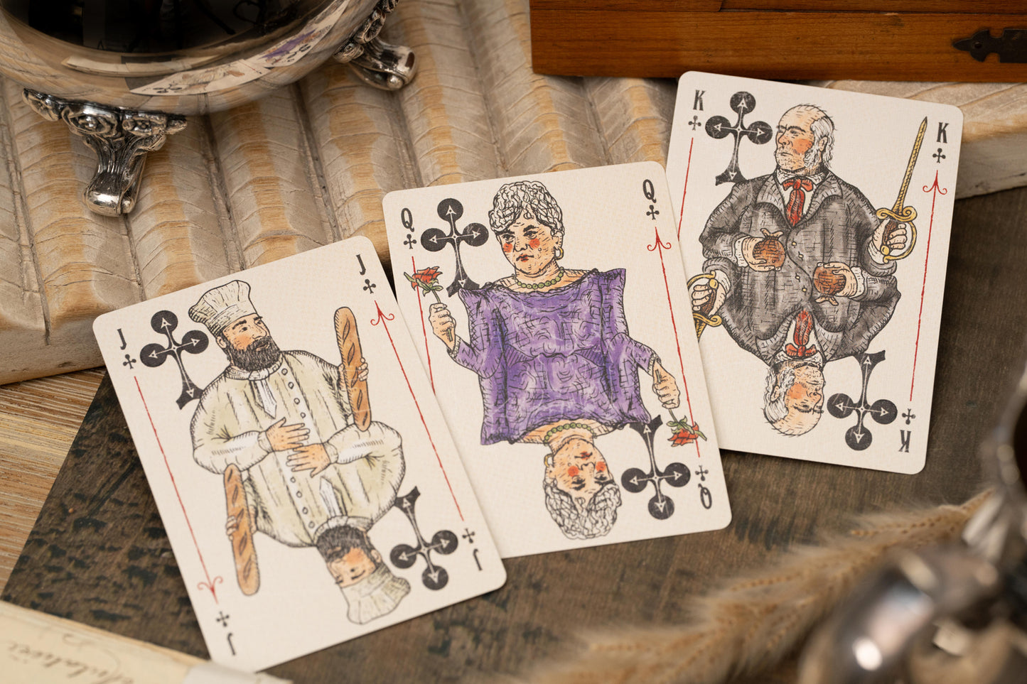 Three playing cards with decorative suits on a wooden surface.