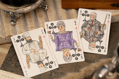 Three playing cards with decorative suits on a wooden surface.