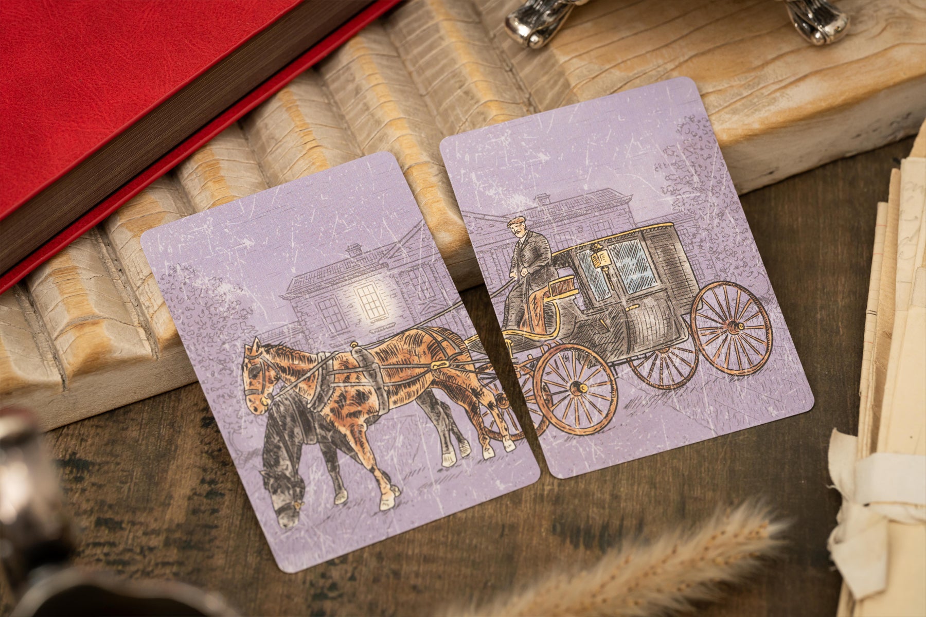 Two playing cards with horse and carriage design on a wooden surface - hand illustrated joker diptych - love & retribution