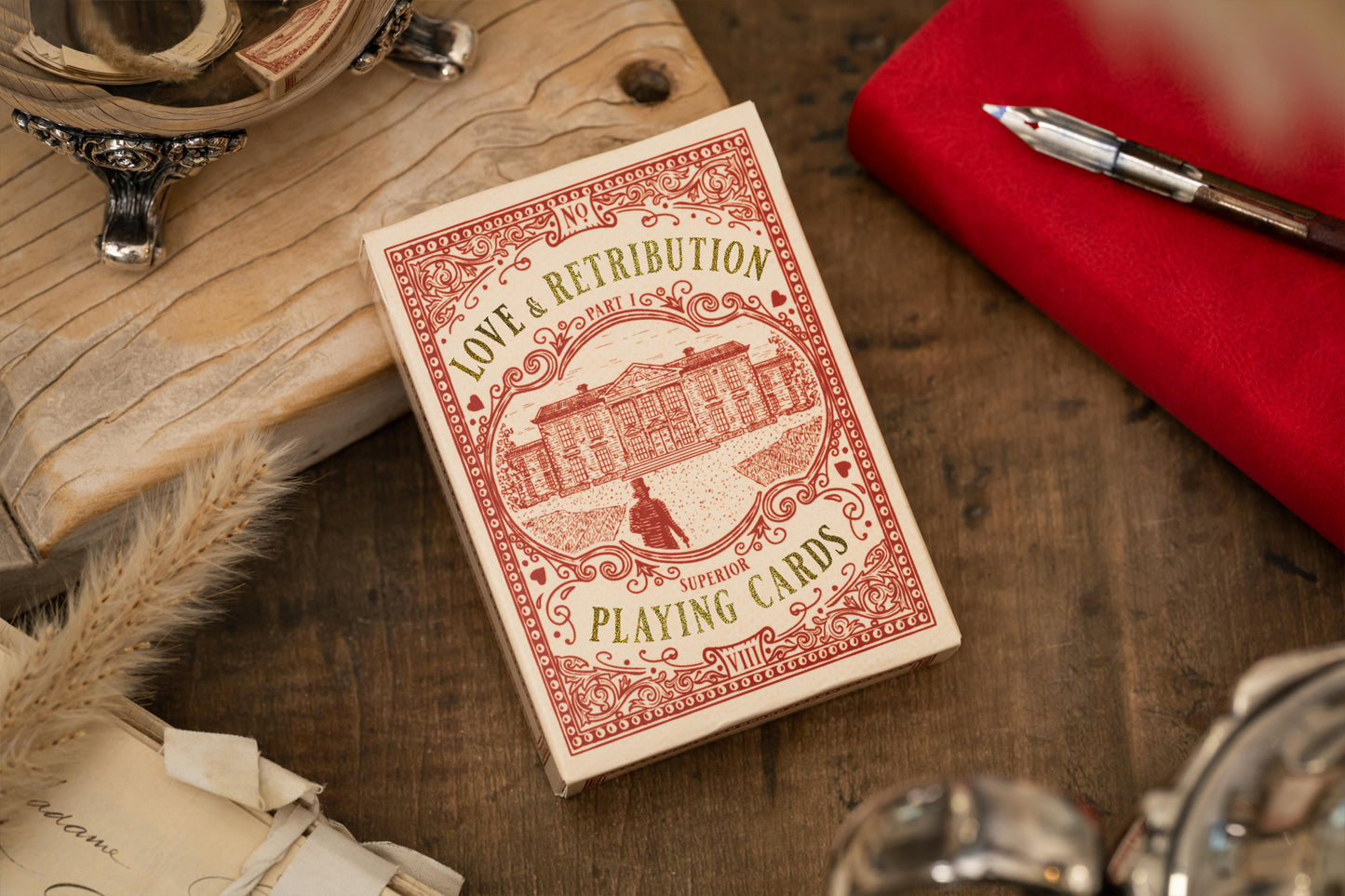 Vintage playing card deck titled 'Love & Retribution' on a wooden surface with premium decorative items.