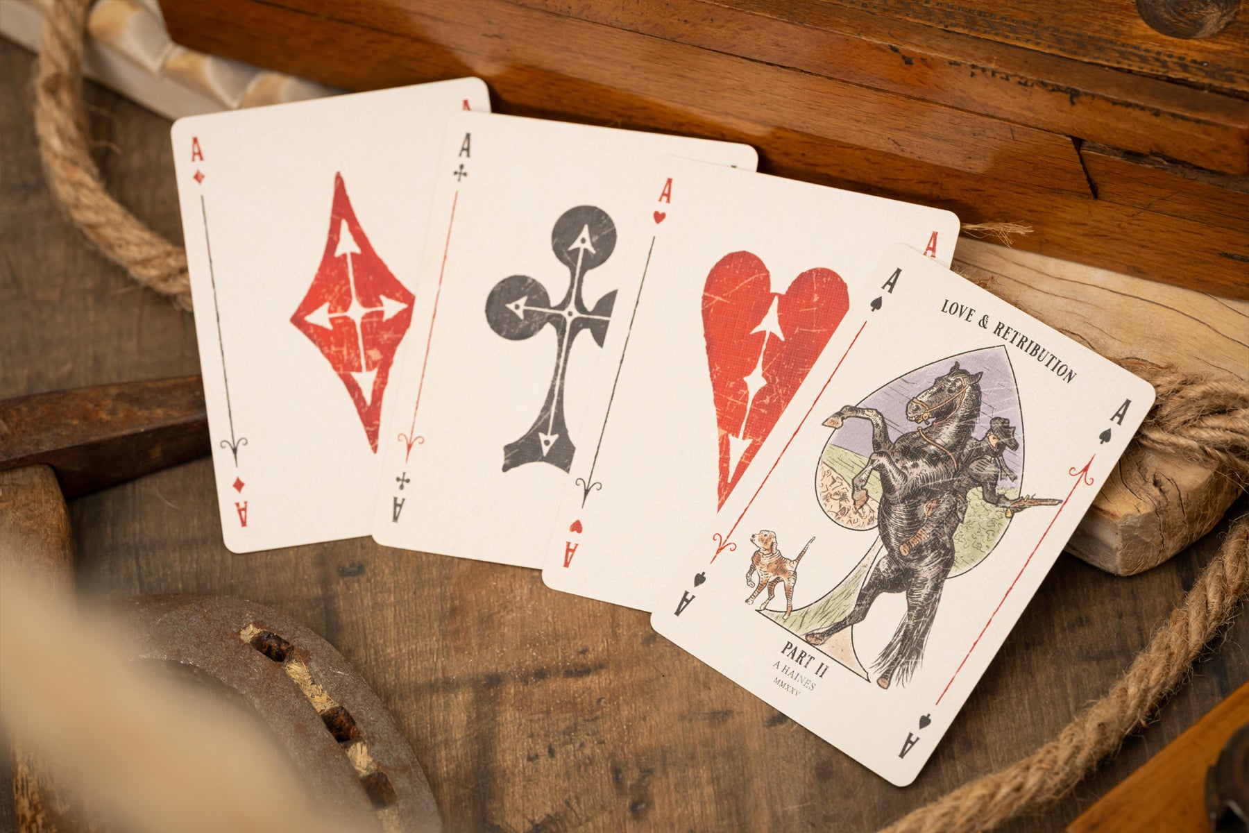 Four vintage luxury playing cards with unique designs on a wooden surface