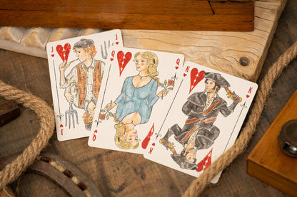 Three vintage playing cards featuring characters on a wooden surface with rope.