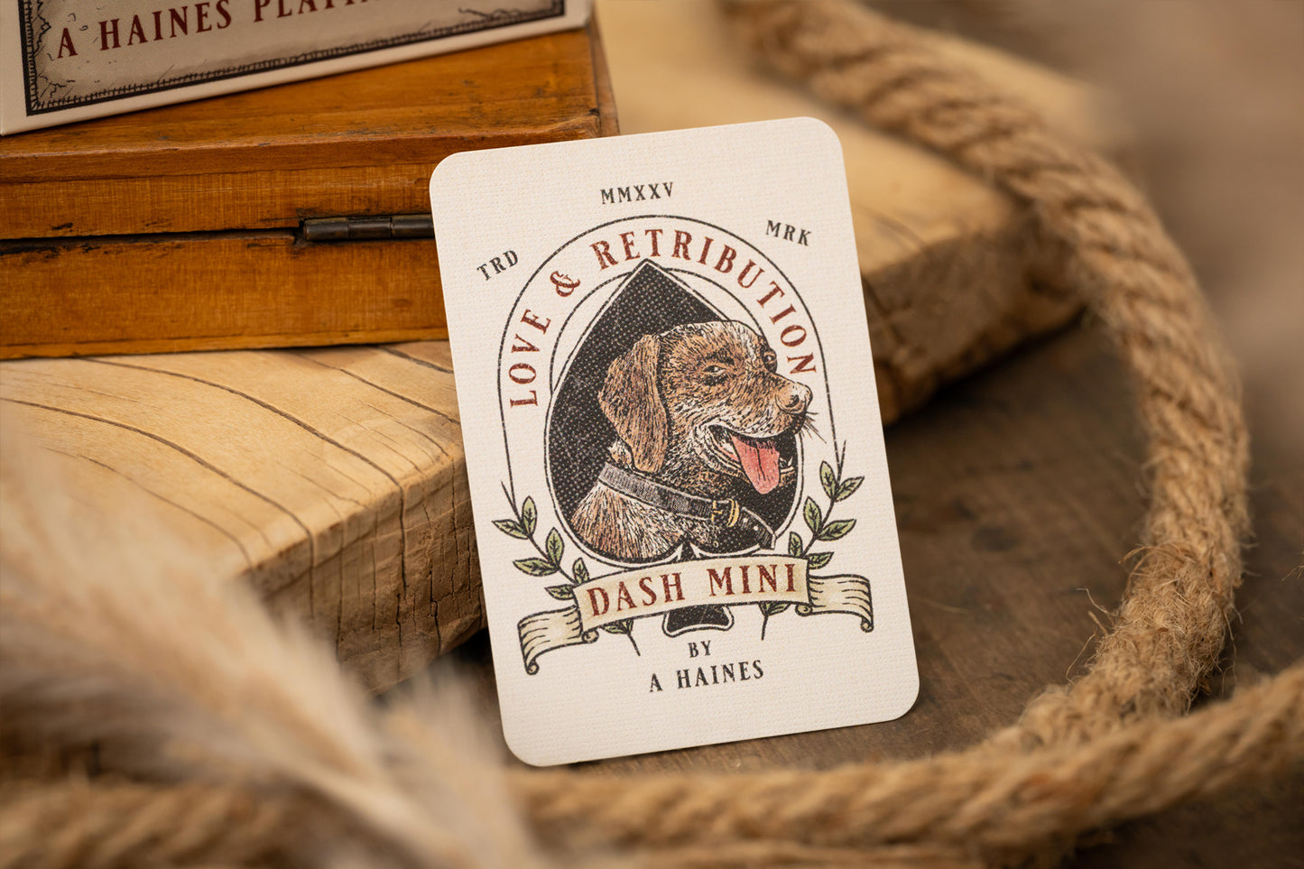 Vintage-style card with a dog illustration and text on a wooden surface with rope.