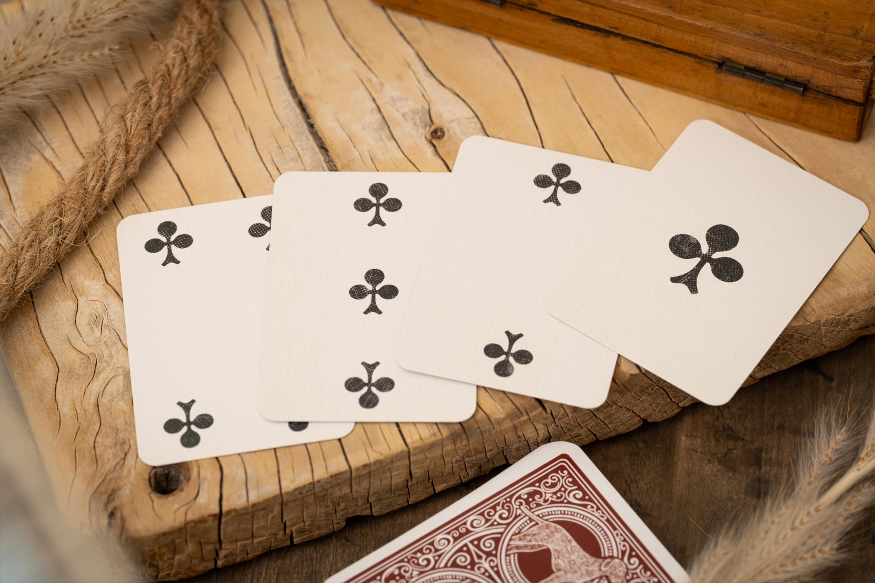 Four playing cards with club symbols on a wooden surface