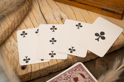 Four playing cards with club symbols on a wooden surface
