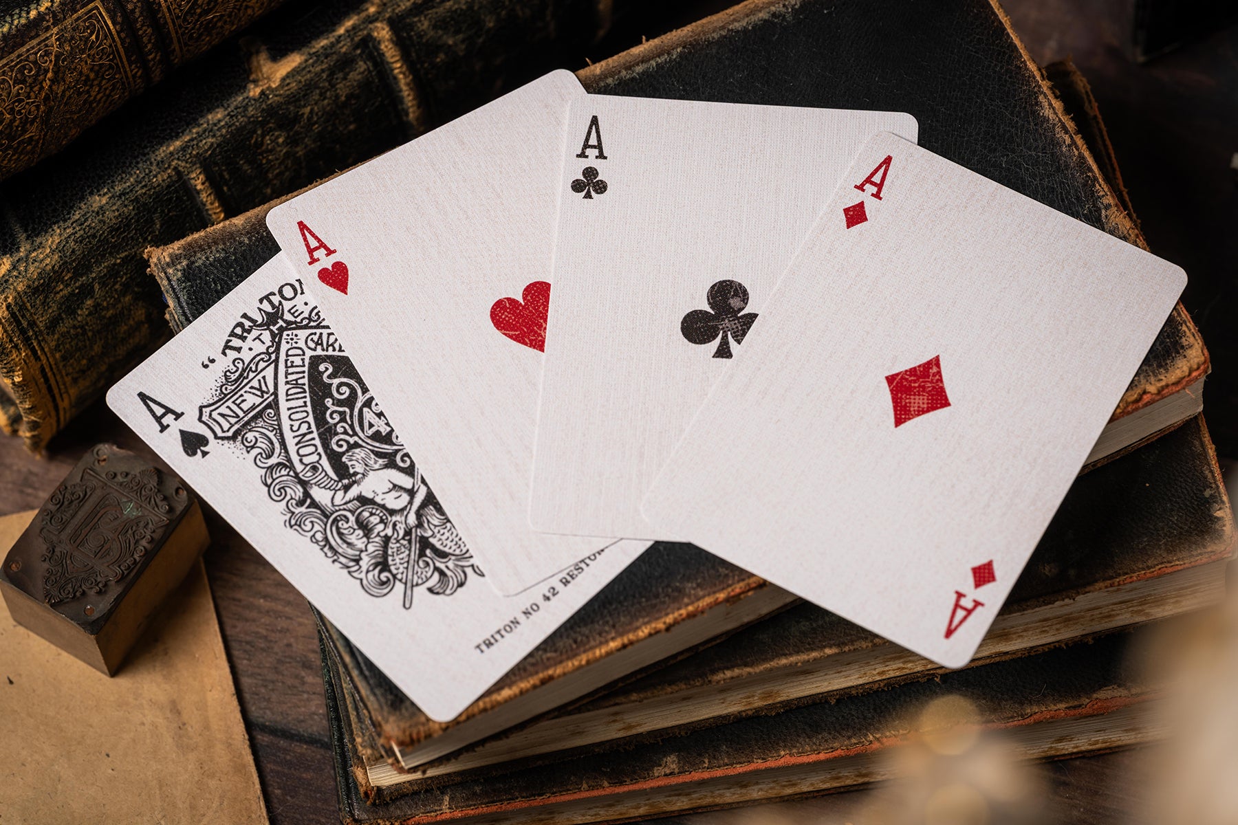 Four playing cards showing aces from different suits on an old book