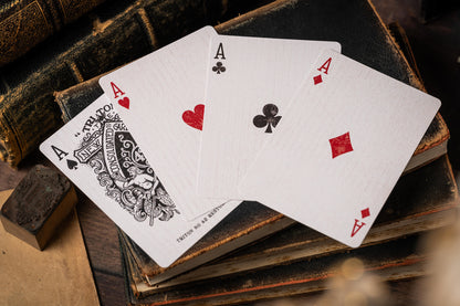 Four playing cards showing aces from different suits on an old book