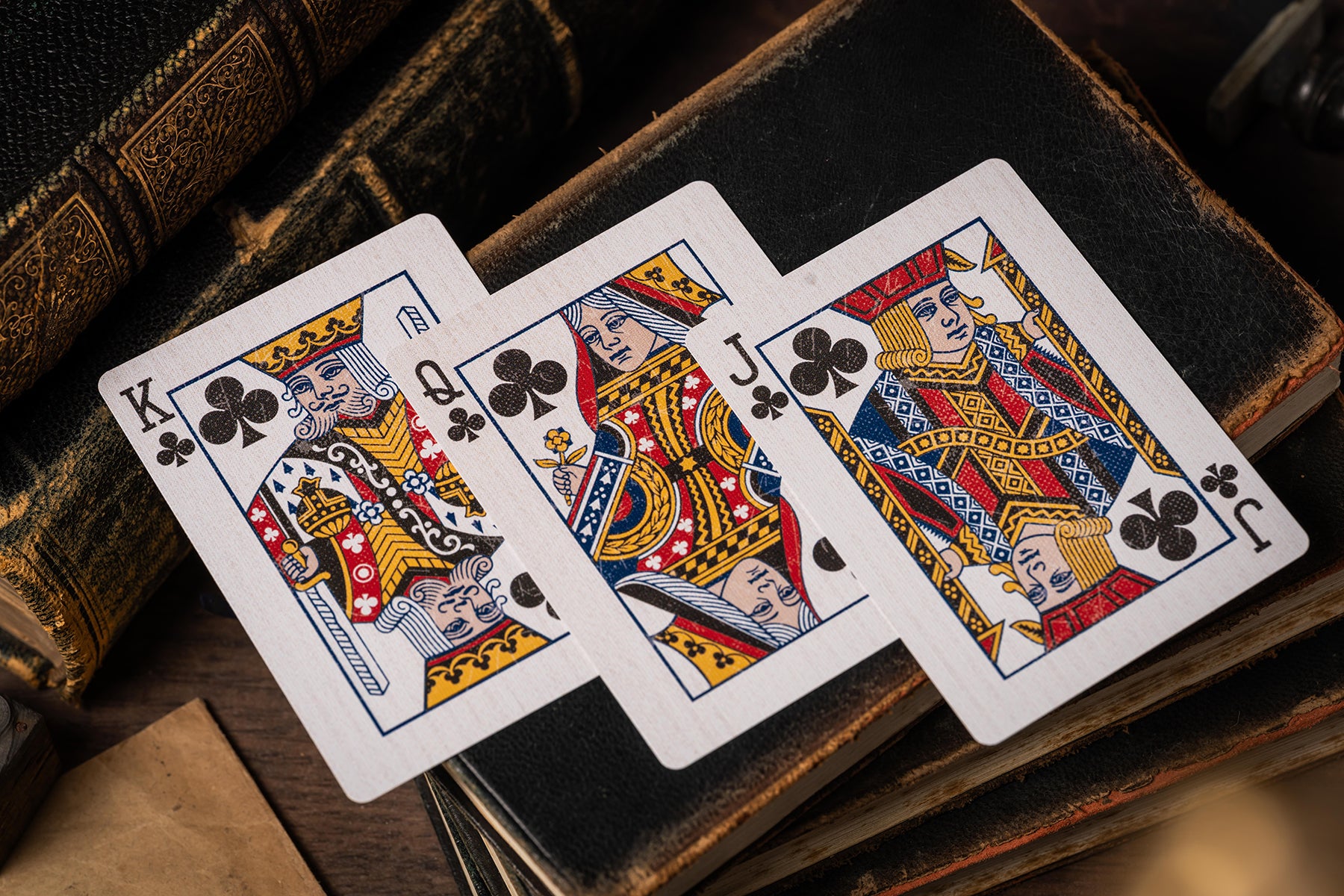 Three playing cards (King, Queen, Jack of Clubs) on an old book