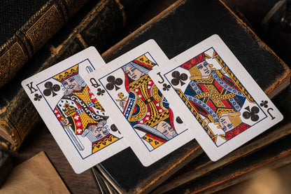 Three playing cards (King, Queen, Jack of Clubs) on an old book