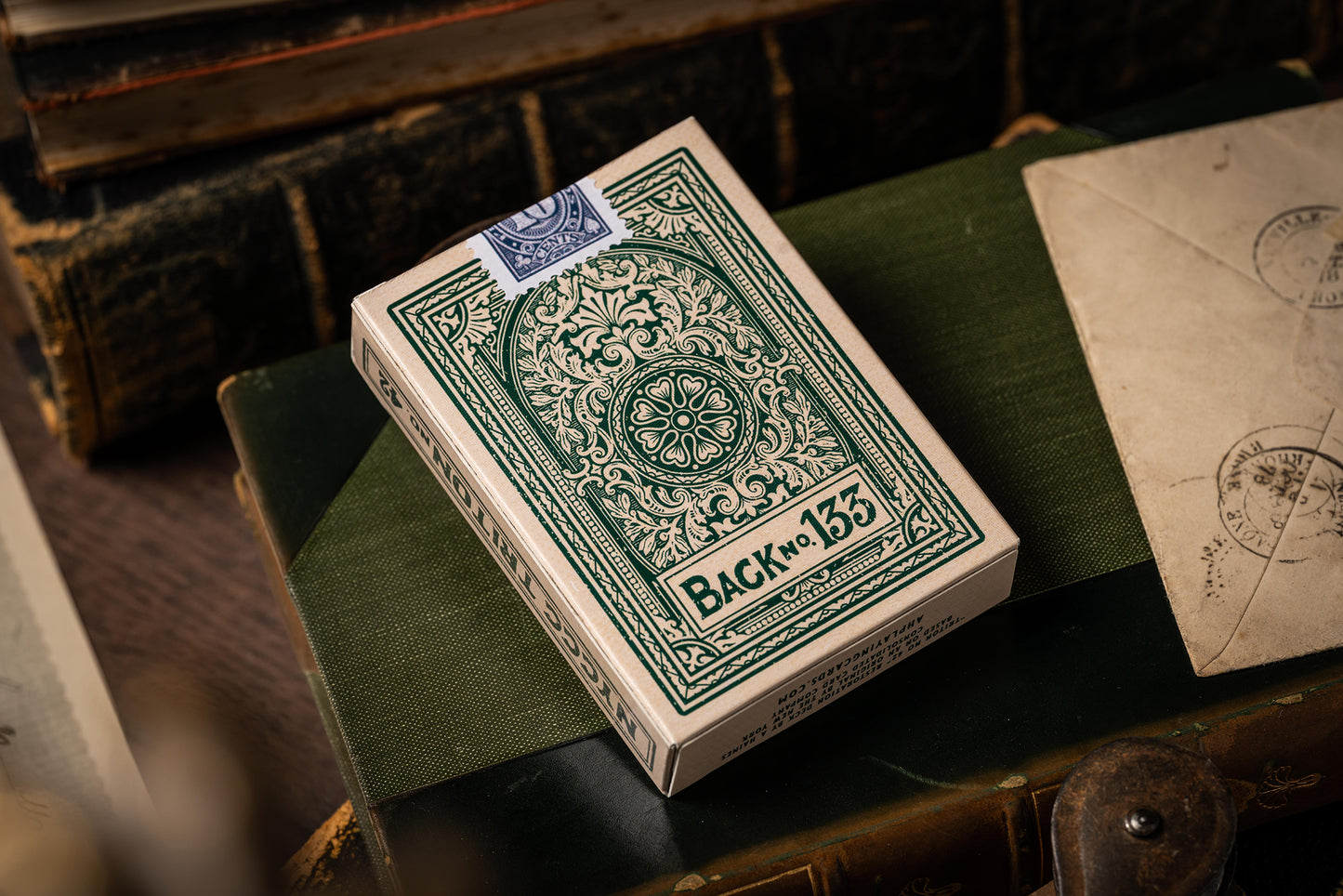 Green and white playing card box with intricate design on a wooden surface.