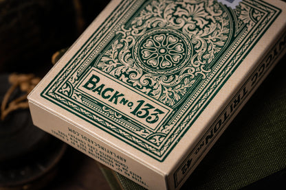 Close-up of a deck of playing cards with decorative green design on the back