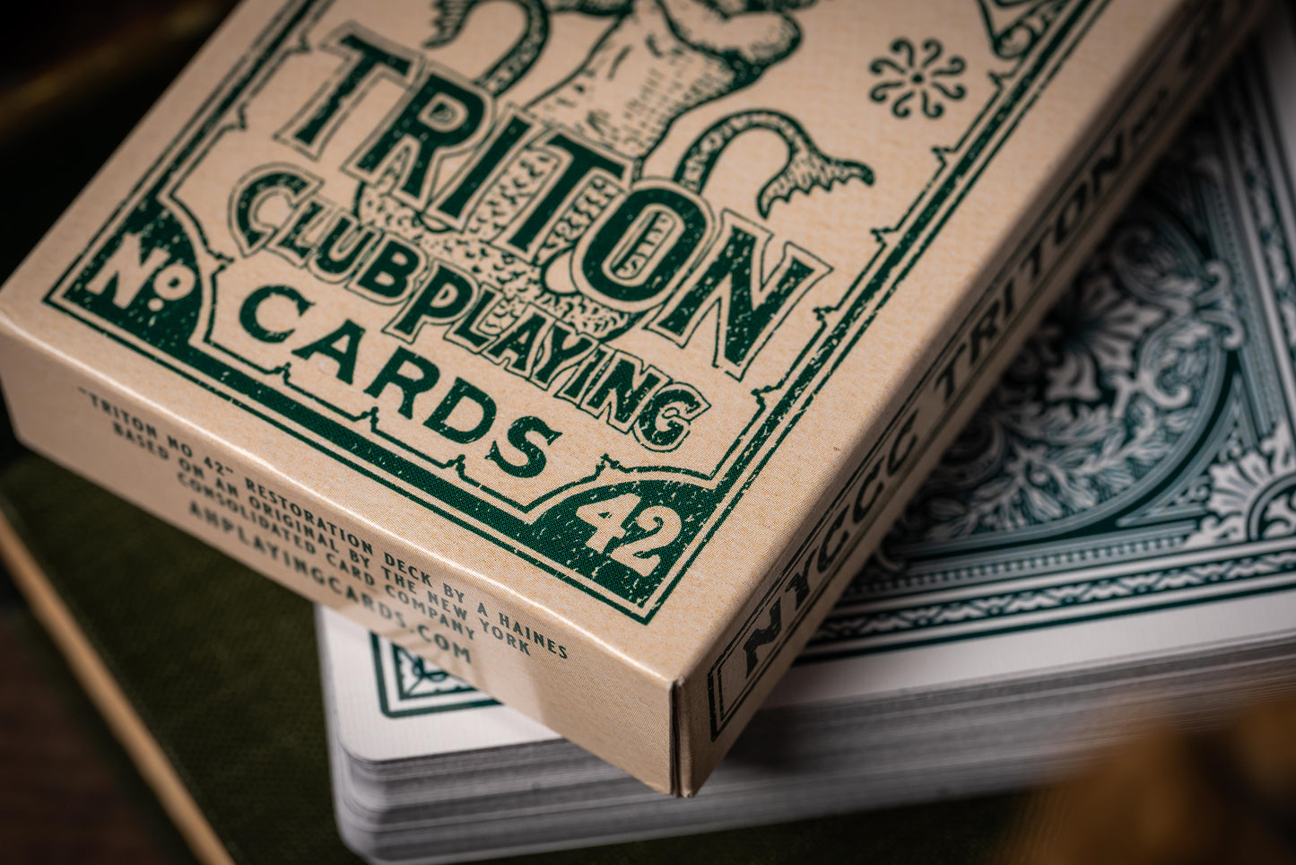Close-up of vintage Triton Club Playing Cards packaging with green text on a brown background.