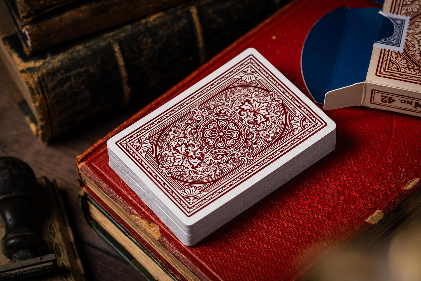 Red and white vintage playing card deck on a red surface with vintage books and cards in the background