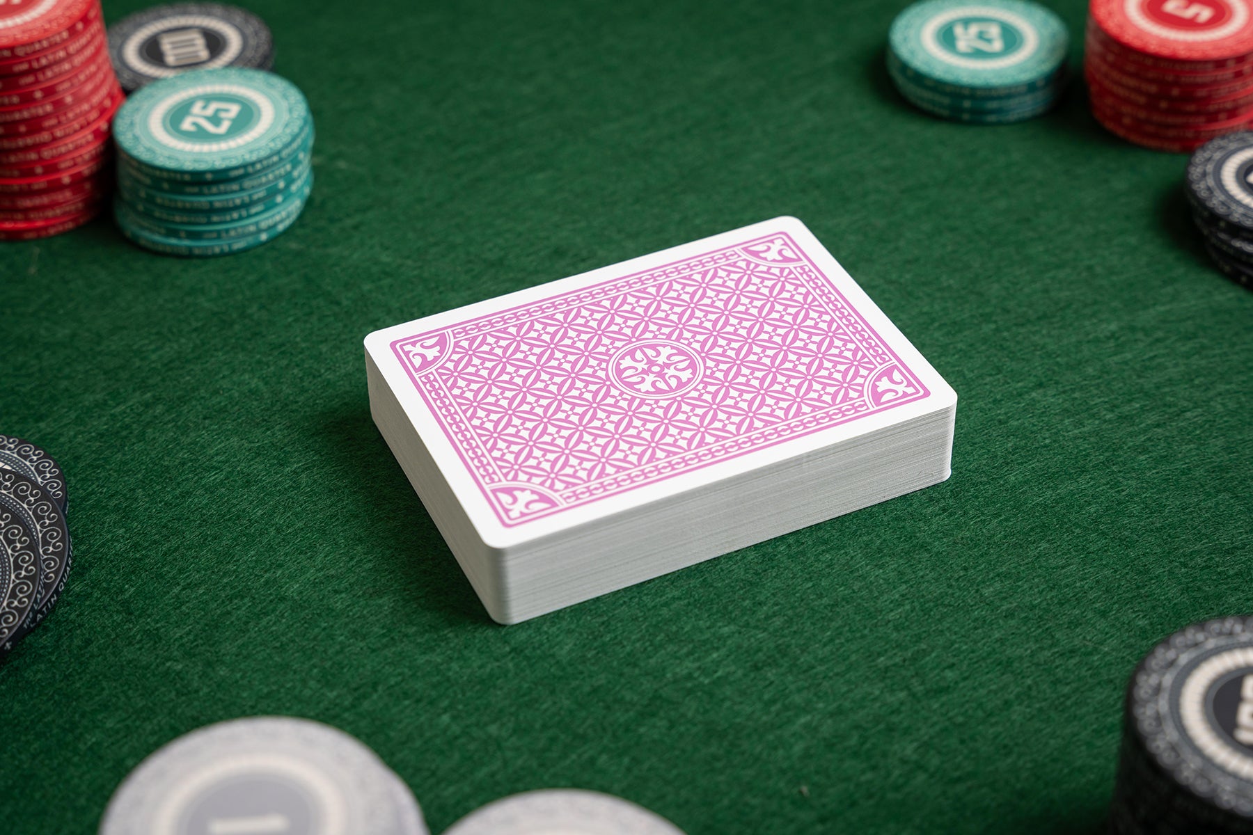 purple deck of plastic playing cards on a green felt poker table with poker chips.