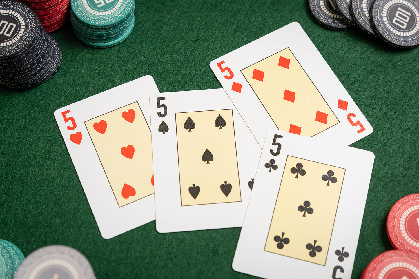 premium pvc Poker playing cards with fives and poker chips on a green felt table