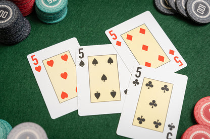 premium pvc Poker playing cards with fives and poker chips on a green felt table