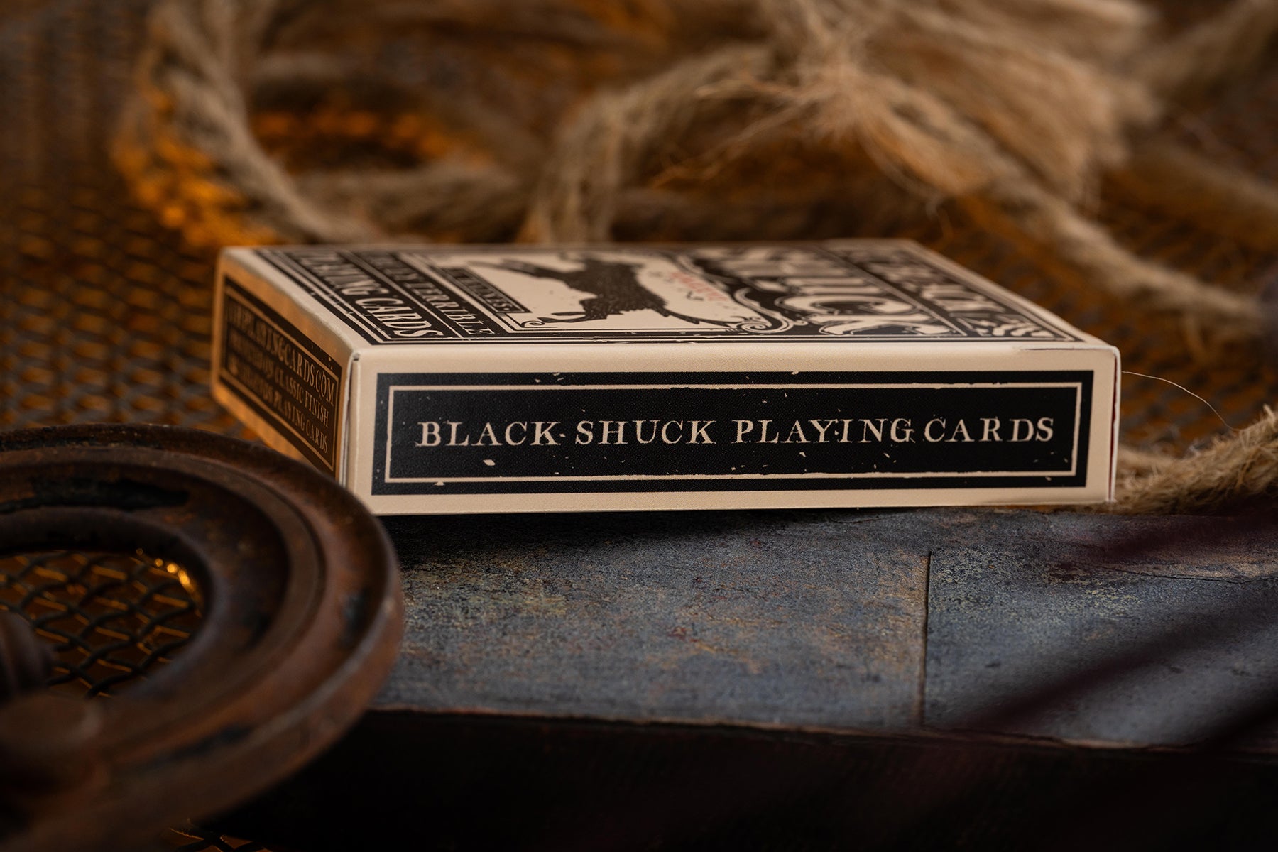 Black-Shuck playing cards on a rustic background with rope and metal objects.