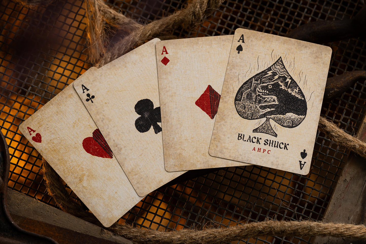 Four vintage british playing cards, including the Ace of Spades, on a textured surface.