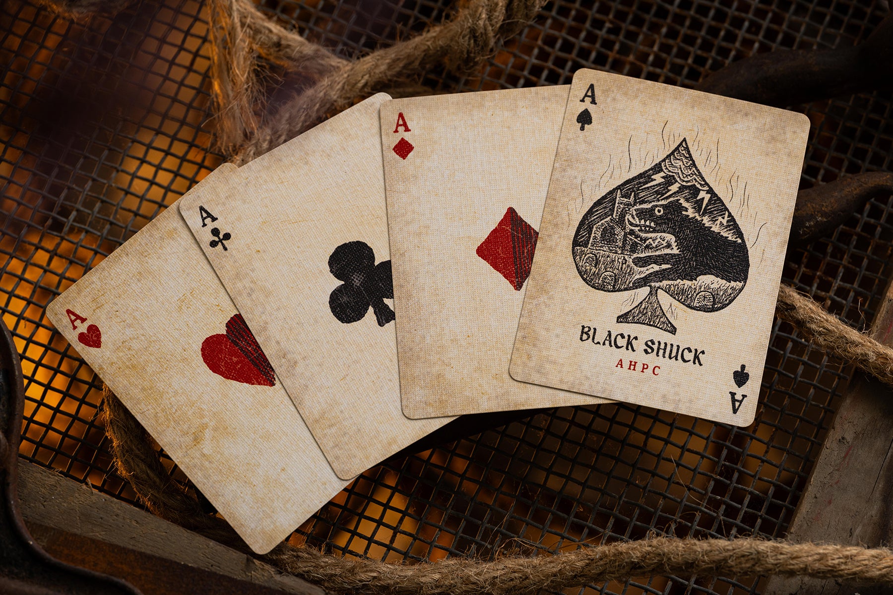 Four vintage british playing cards, including the Ace of Spades, on a textured surface.