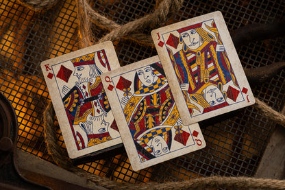 Three playing cards featuring kings on a textured surface with ropes.
