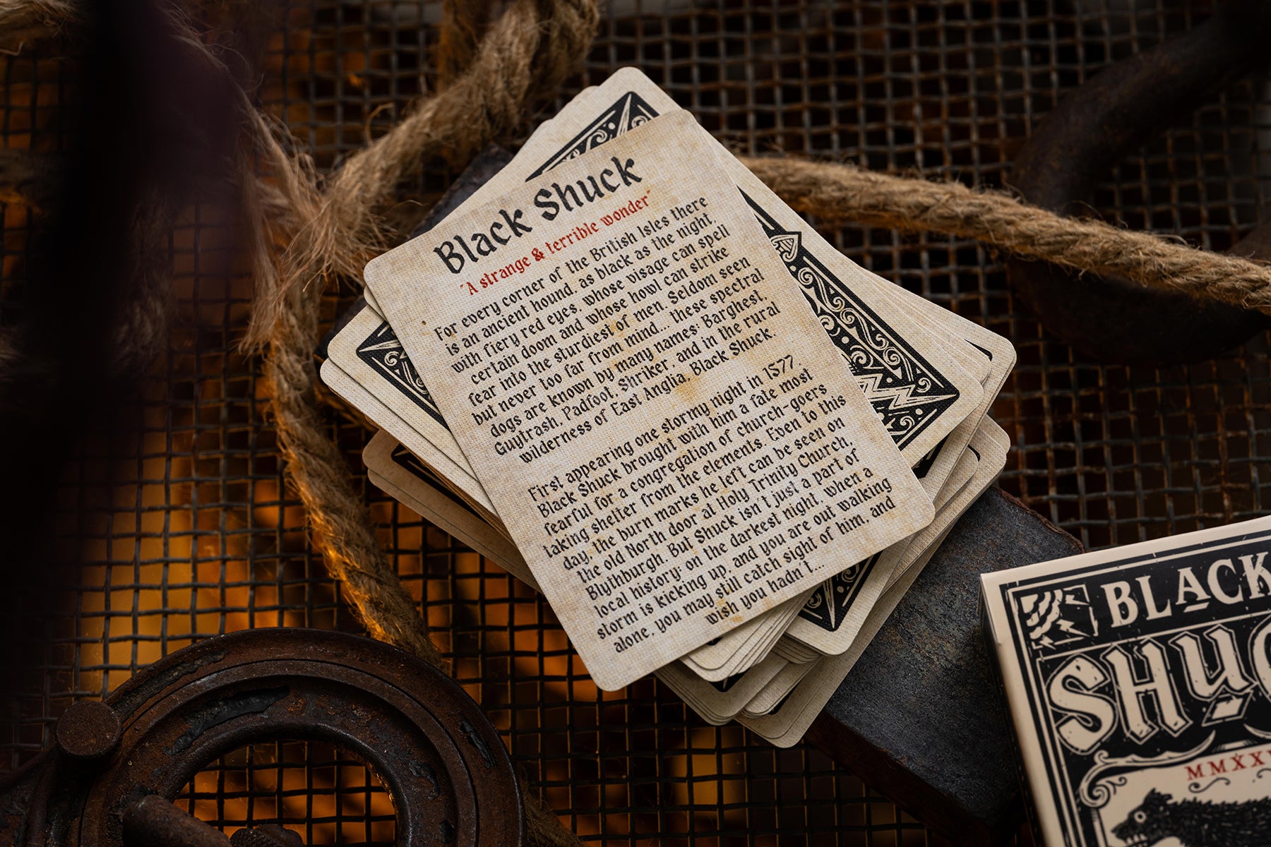 Stack of playing cards with 'Black Shuck' text on a rustic background