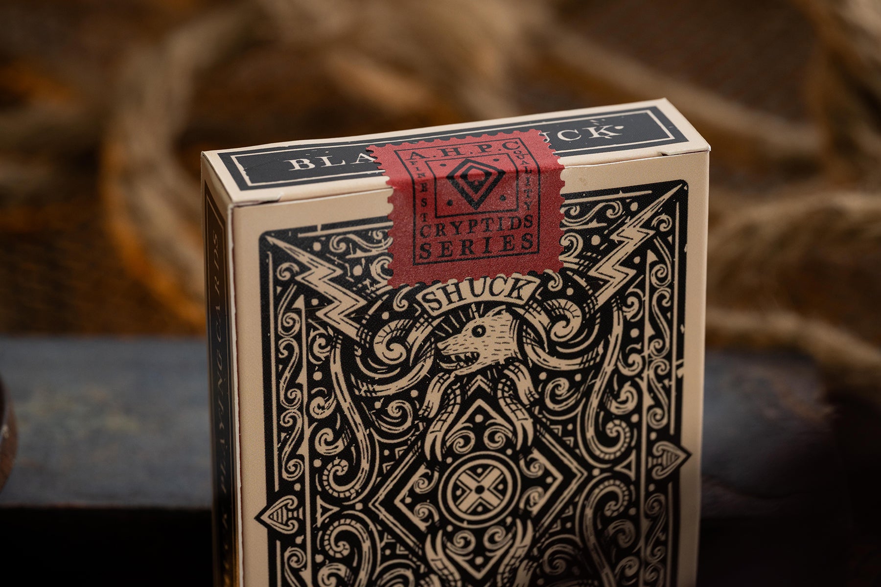 Playing card box with intricate design and 'Black' label on a blurred background