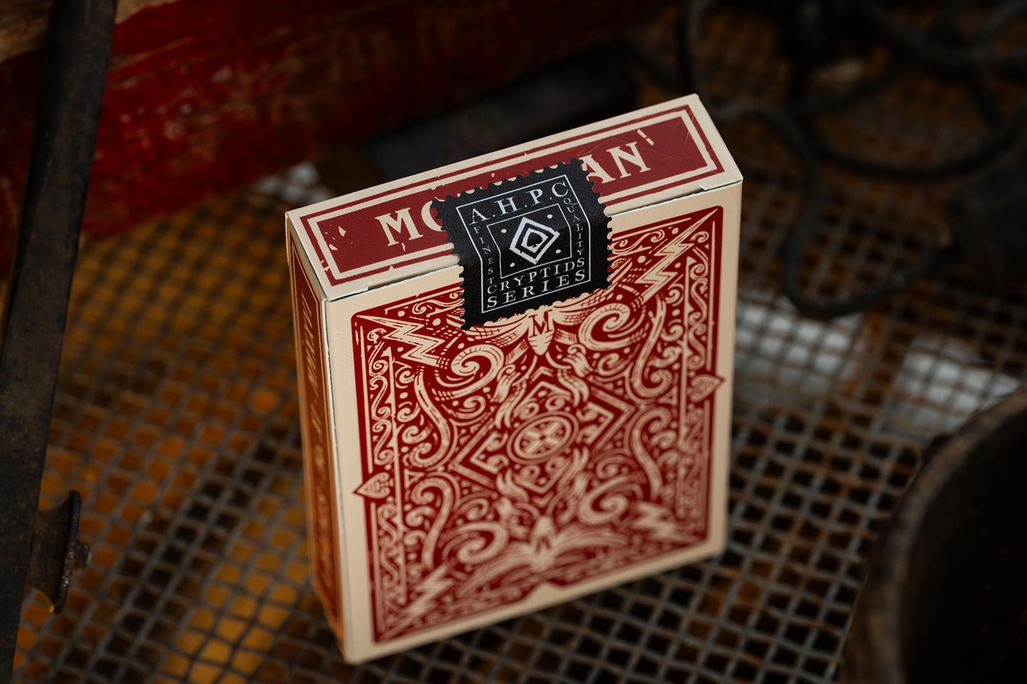 Red playing card box with intricate design on a textured surface