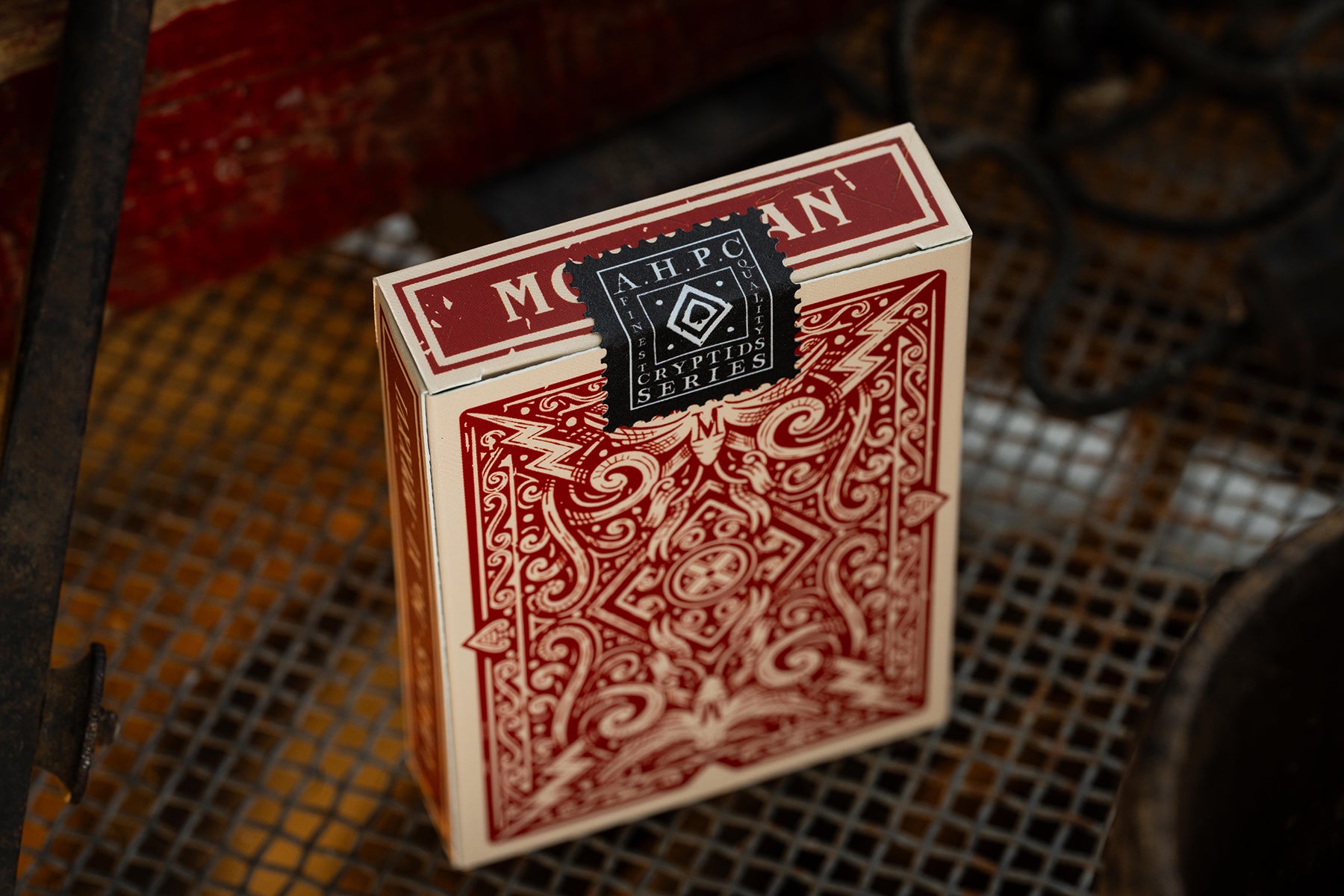 Red playing card box with intricate design on a textured surface