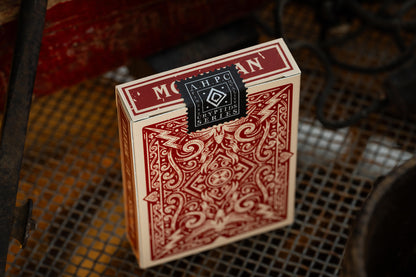 Red playing card box with intricate design on a textured surface