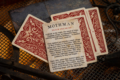 Playing cards featuring Mothman on a textured surface