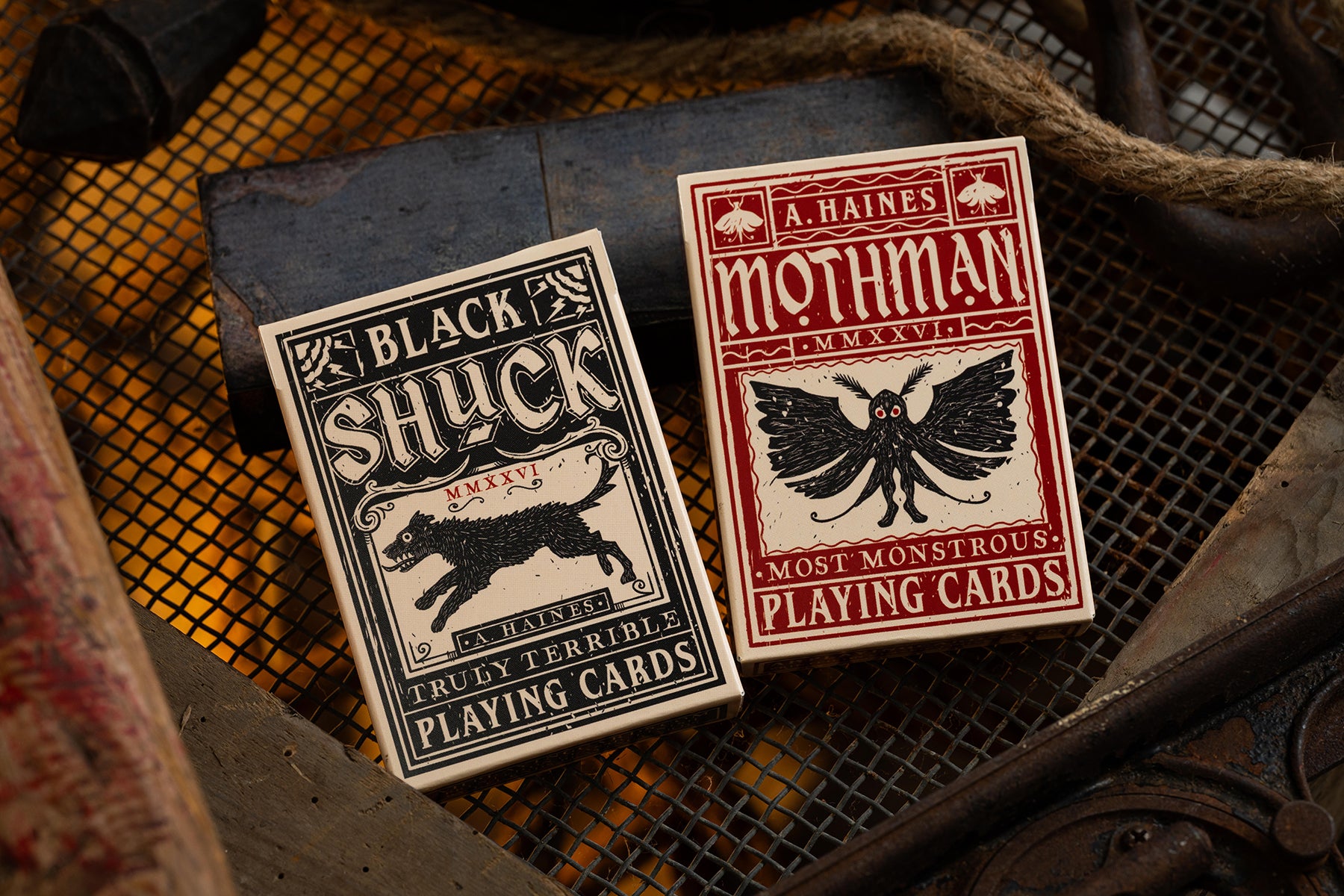 Two playing card decks, 'Black Shuck' and 'Mothman', on a textured surface.
