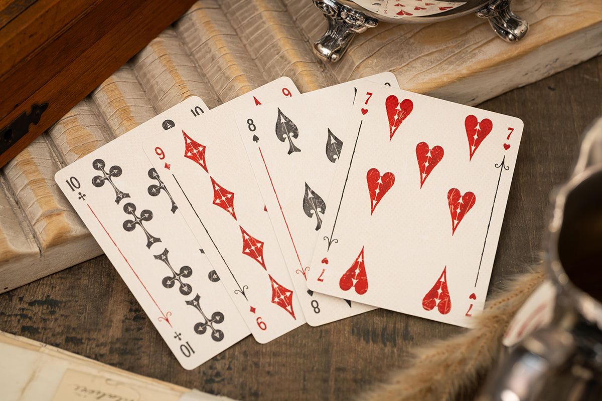 Four premium vintage playing cards on a wooden surface with a clock in the background - UK design