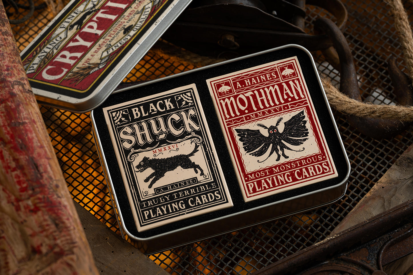 Two decks of vintage cryptids playing cards in gentlemans gift tin with distinctive labels on a textured surface.