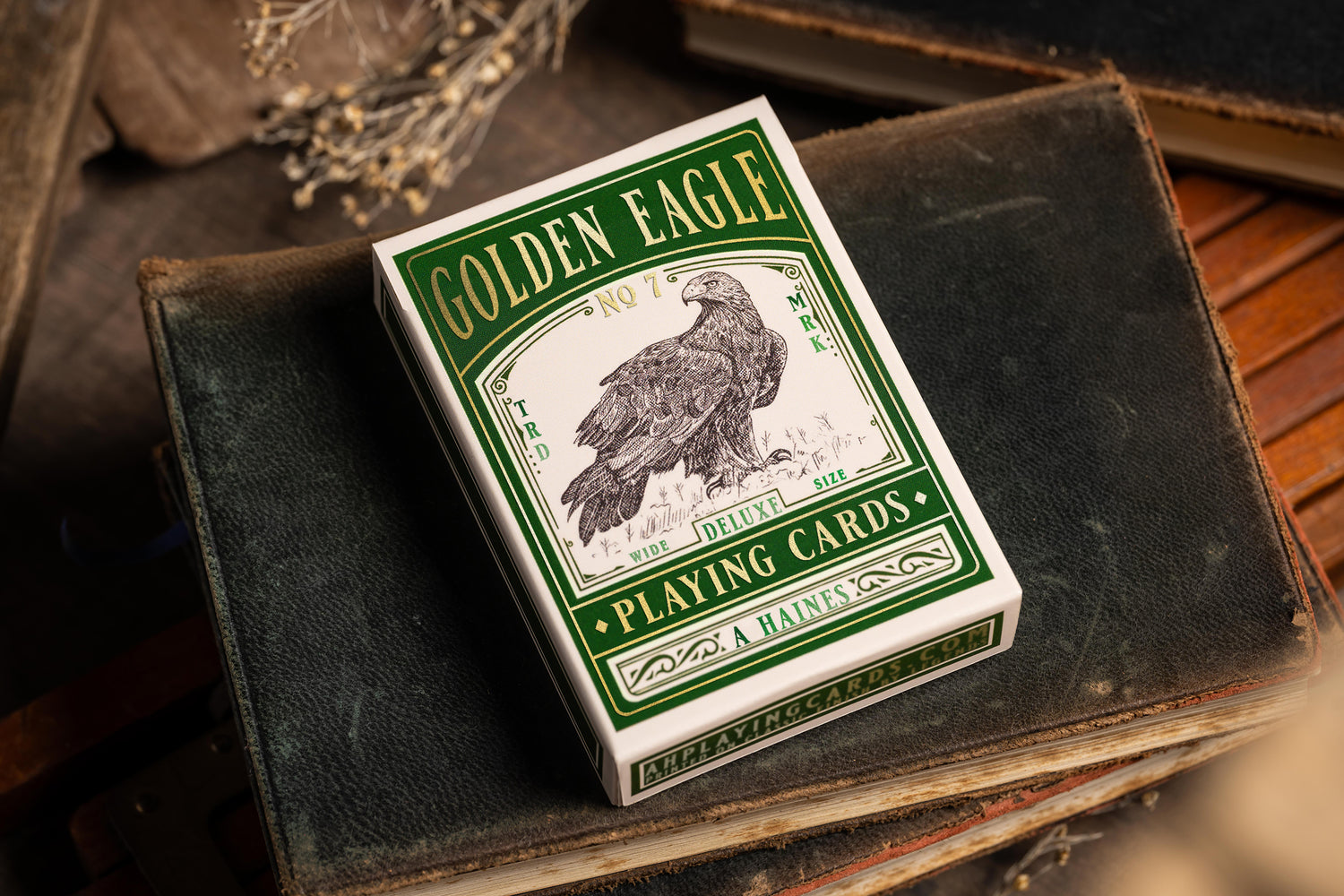 image showing front angle tuckbox of premium playing cards in a vintage style    - Golden Eagle vintage playing cards - resting on antique book