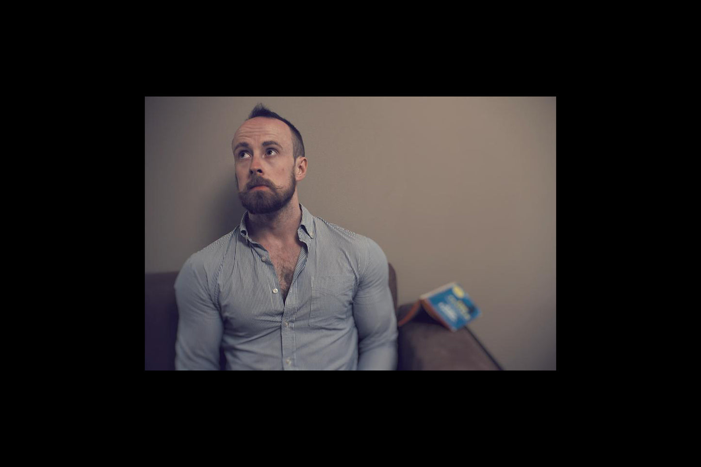 UK Magician John Galsworthy sitting on a couch with a neutral expression, blurred background - Cards in Common playing card convention 2026